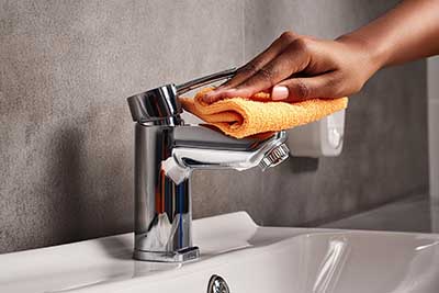 Hand beim Putzen von Badarmatur