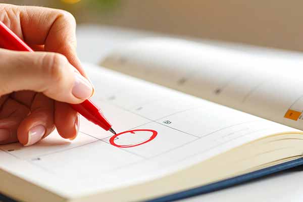 Hand markiert einen Termin in einem Kalender