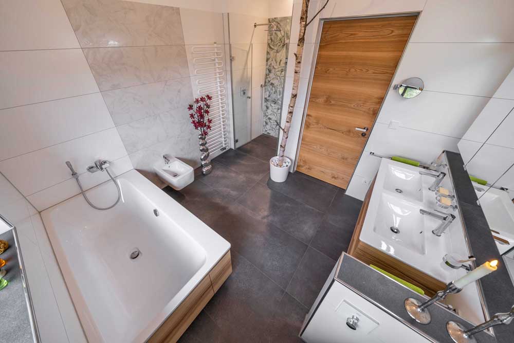 Betzl Haustechnik Referenzbad mit Doppelwaschtisch, großer Dusche, Birkenstamm als Dekoelement - Blick von oben auf Wanne und Dusche